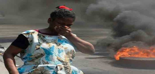 Haiti_woman_passes_burning_tires_AFP_GettyImages_Clarens_Siffroy